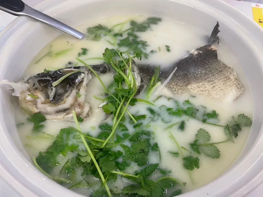 A bowl of fish soup with herbs, used as a visual reference for Tianmu Lake fish head casserole.