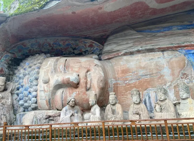 A large reclining sandstone Buddha carving surrounded by green bamboo at Baodingshan in Dazu.