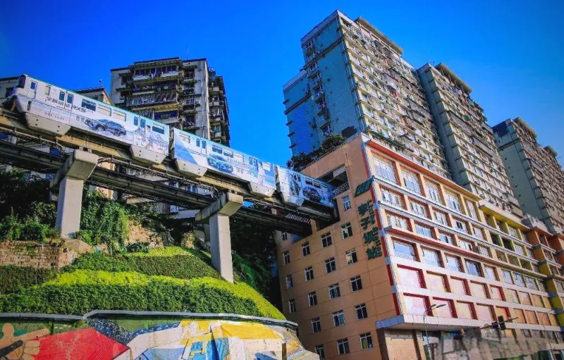 A yellow monorail train passing through a hole in the middle of a multi-story residential apartment block in Chongqing.