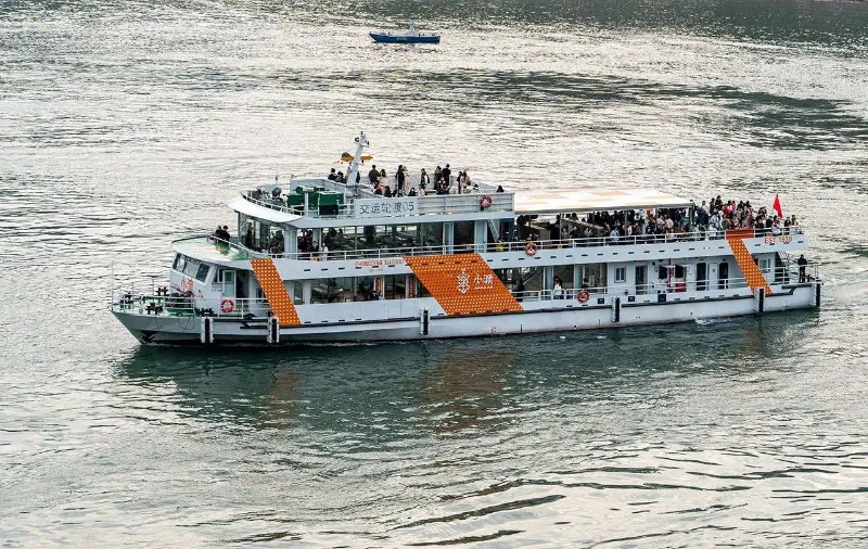 A public passenger ferry navigating the narrow, mist-shrouded passage of Qutang Gorge under the towering cliffs of Kuimen Gate.