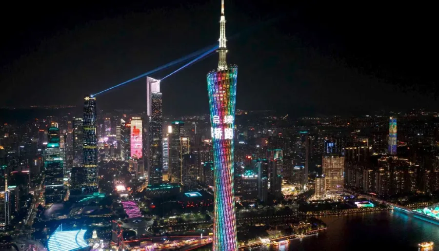 The Canton Tower illuminated at night, towering over the Pearl River and Zhujiang New Town skyline.