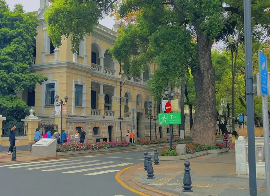 A quiet tree-lined street on Shamian Island with European-style colonial buildings.