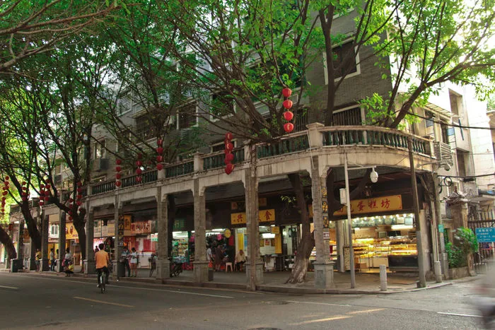 A narrow lane in Yongqing Fang, Guangzhou, with traditional brick buildings, decorative wooden doors, and green plants.