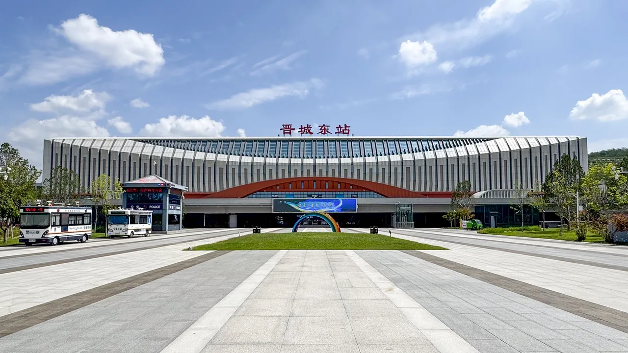 The forecourt and wave-shaped roof of Jincheng East high-speed railway station under blue sky.