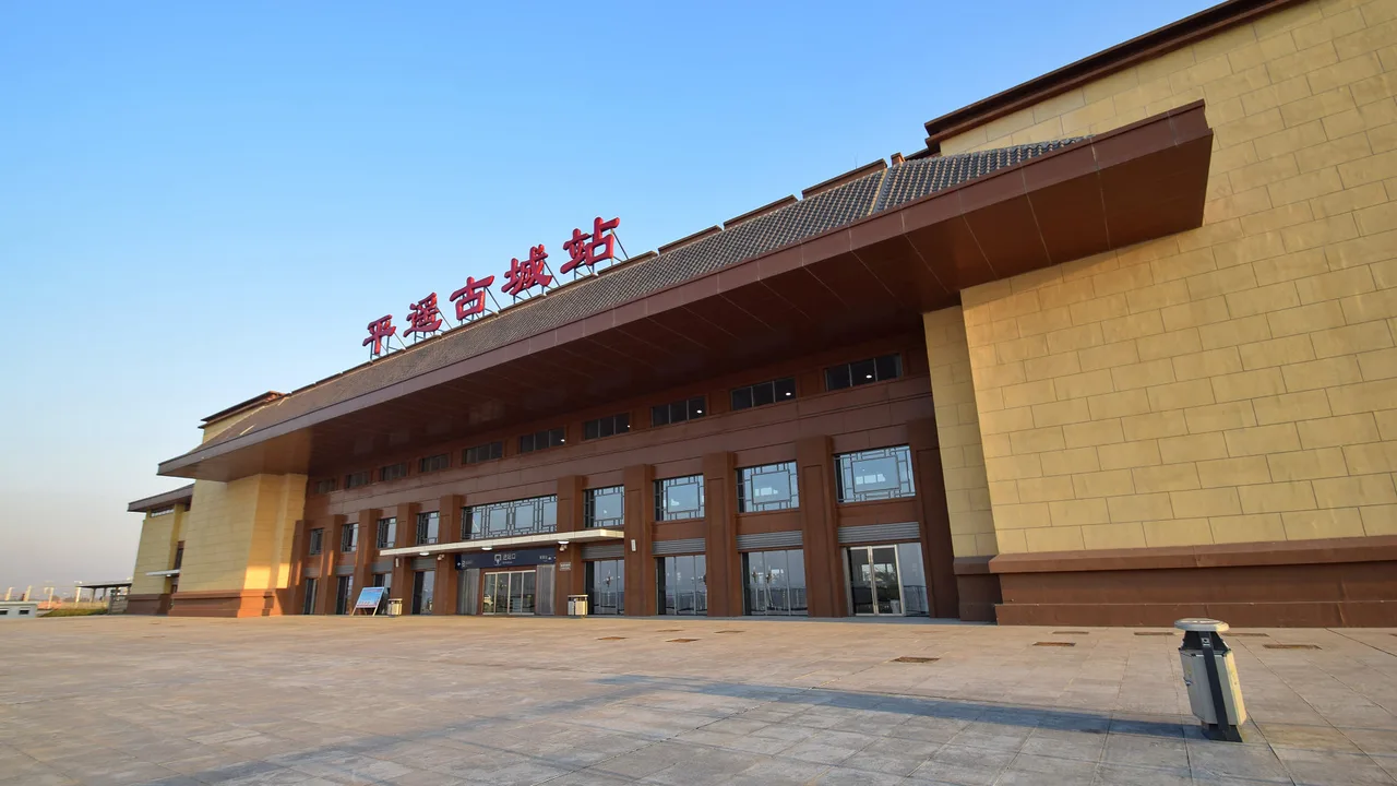 The station building of Pingyao Gucheng high-speed railway station under a blue sky.