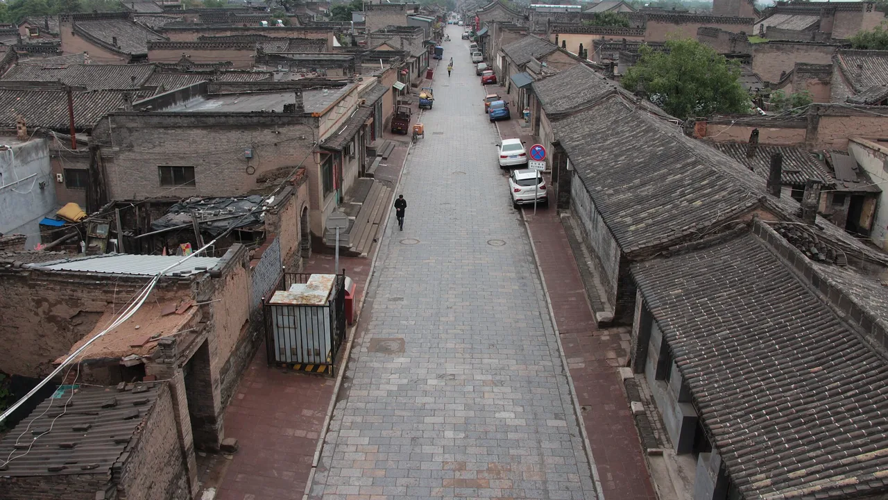 A view along a Pingyao lane lined with grey-tiled courtyard roofs, seen from the city wall.