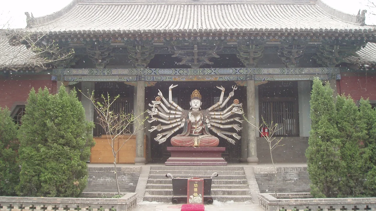 A hall at Shuanglin Temple near Pingyao with a many-armed bodhisattva statue in front of its doorway.