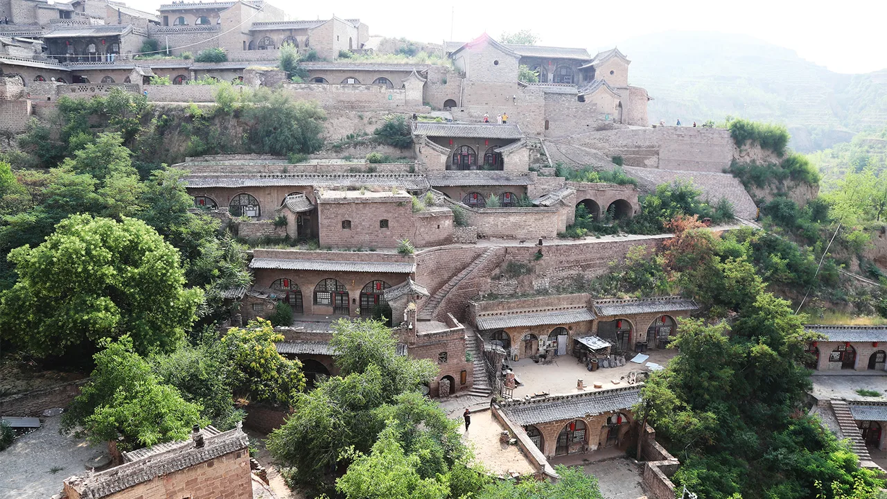 Tiers of stone and brick cave dwellings stacked up the green gully slopes of Lijiashan village, Lin County.