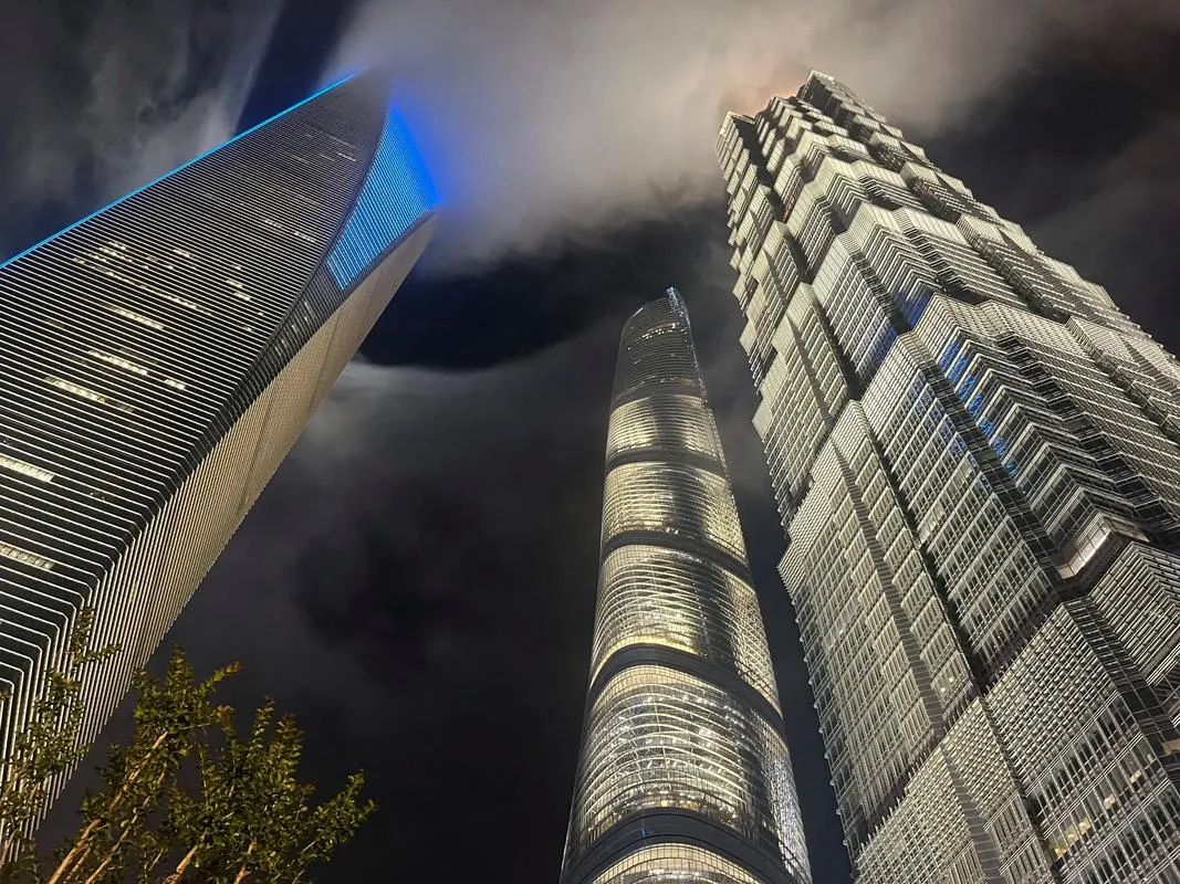 A low-angle view of the Shanghai Tower, Jin Mao Tower, and SWFC rising high into the clouds in Lujiazui, Pudong.