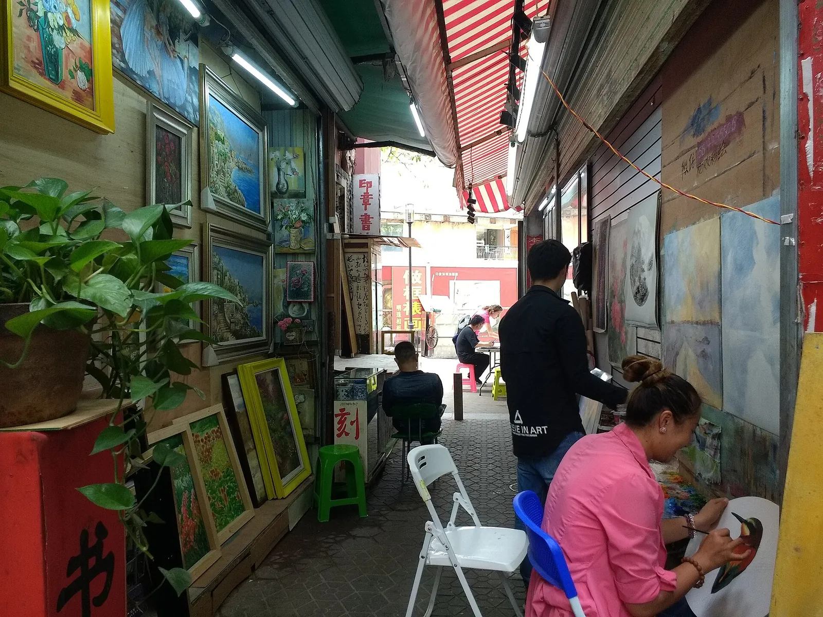 Artists painting canvases in Dafen Oil Painting Village studios