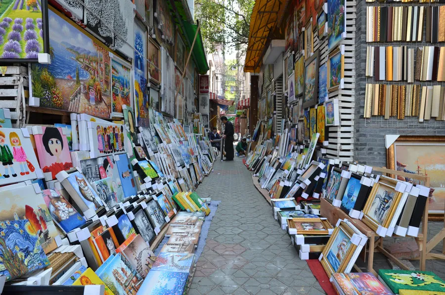 A narrow alleyway in Dafen with colorful oil paintings drying on the brick walls.