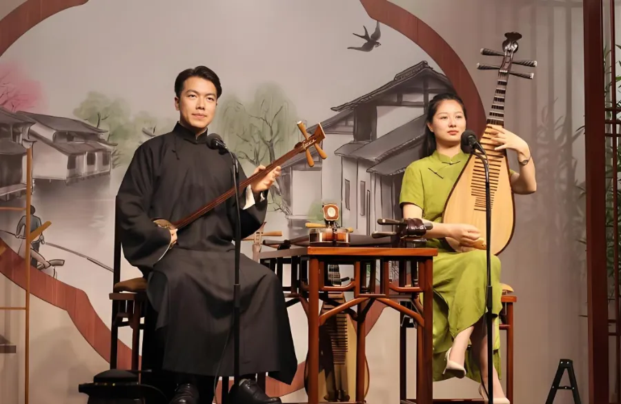A performer playing the pipa on a wooden stage in a traditional Suzhou teahouse.