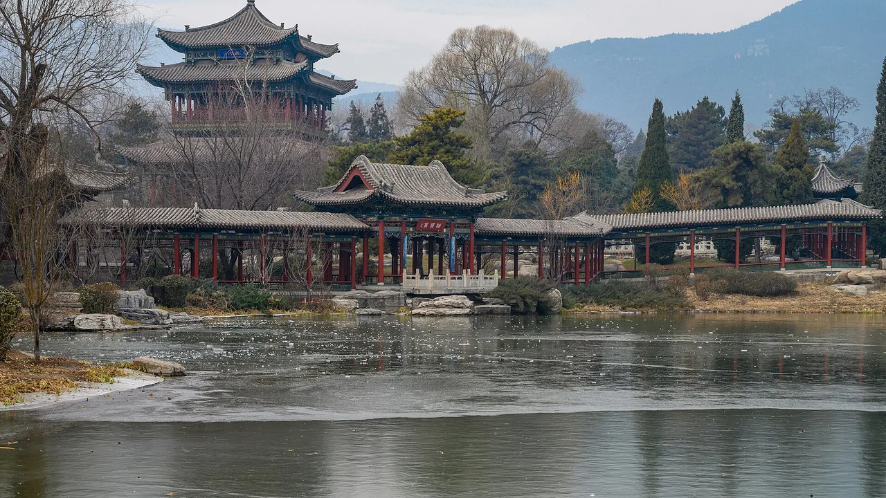Pavilions and temple halls reflected in a spring-fed pond at Jinci, Taiyuan, with hills behind.