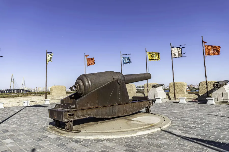 The earthen ramparts and rusted iron cannons of Dagu Fort fortifications overlooking the industrial Binhai coastline.