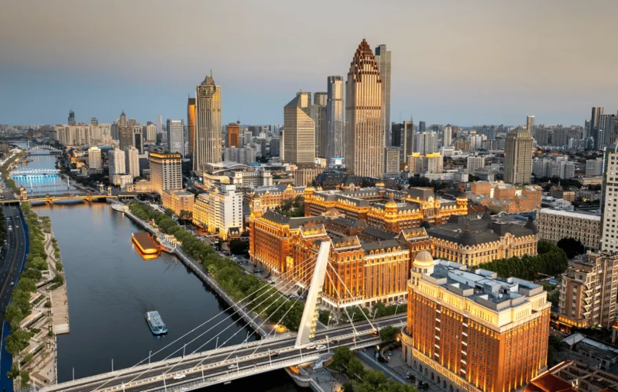 The giant Ferris wheel of the Tianjin Eye rising over the Haihe River at sunset.