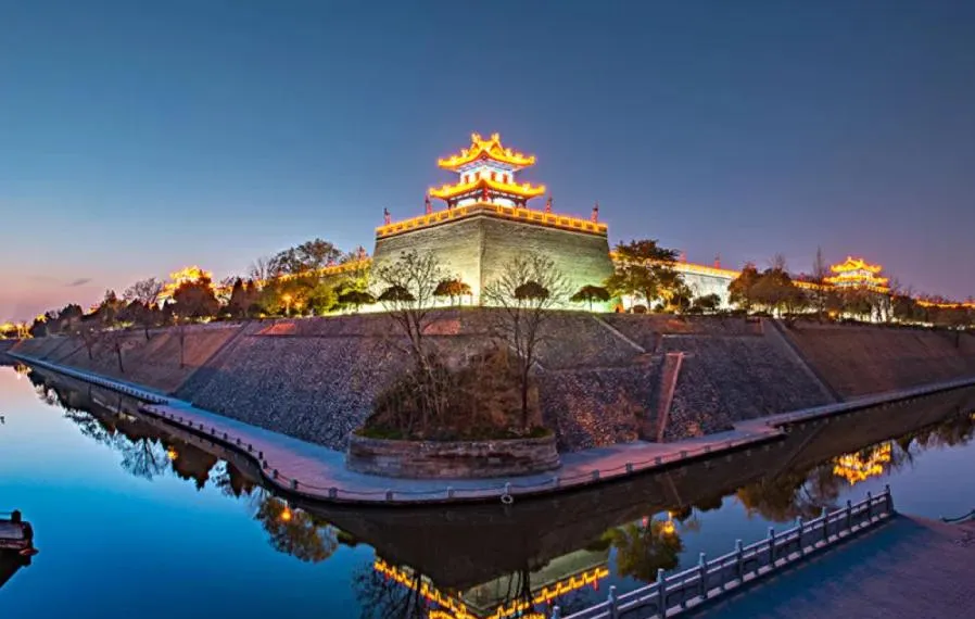 A traveler riding a bicycle along the wide, stone path of the Xi'an City Wall at sunset.