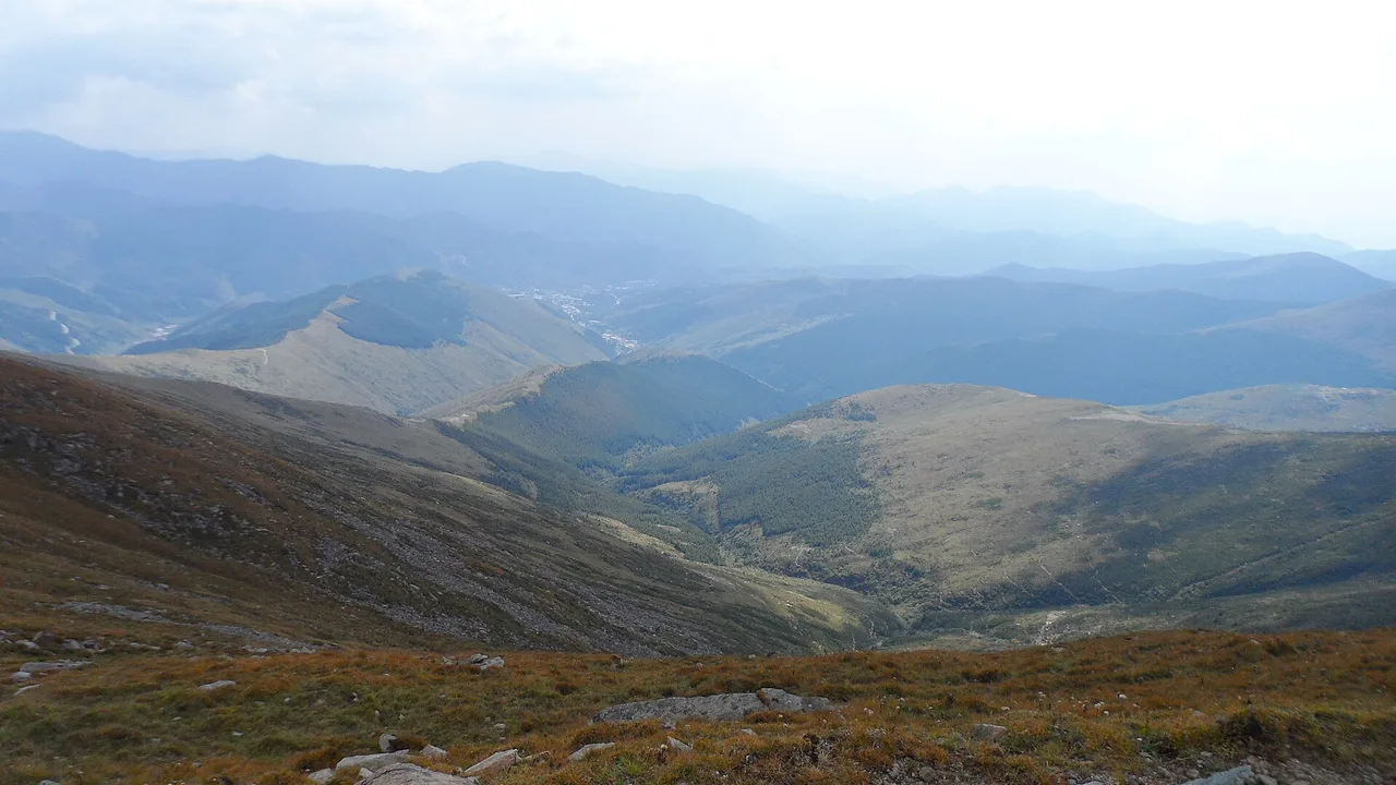 View from Wutai Shan's North Terrace across bare high slopes and rolling ridges under a pale sky.