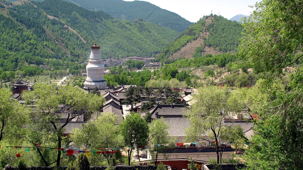 The white stupa of Tayuan Temple rising over Taihuai's monastery roofs, with Wutai Shan's green slopes behind.