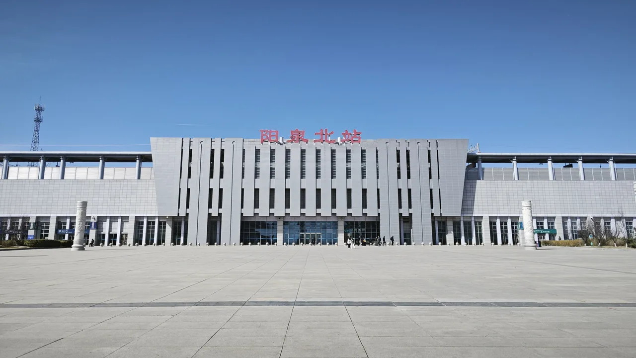 Front façade and forecourt of Yangquan North high-speed railway station under a clear blue sky.