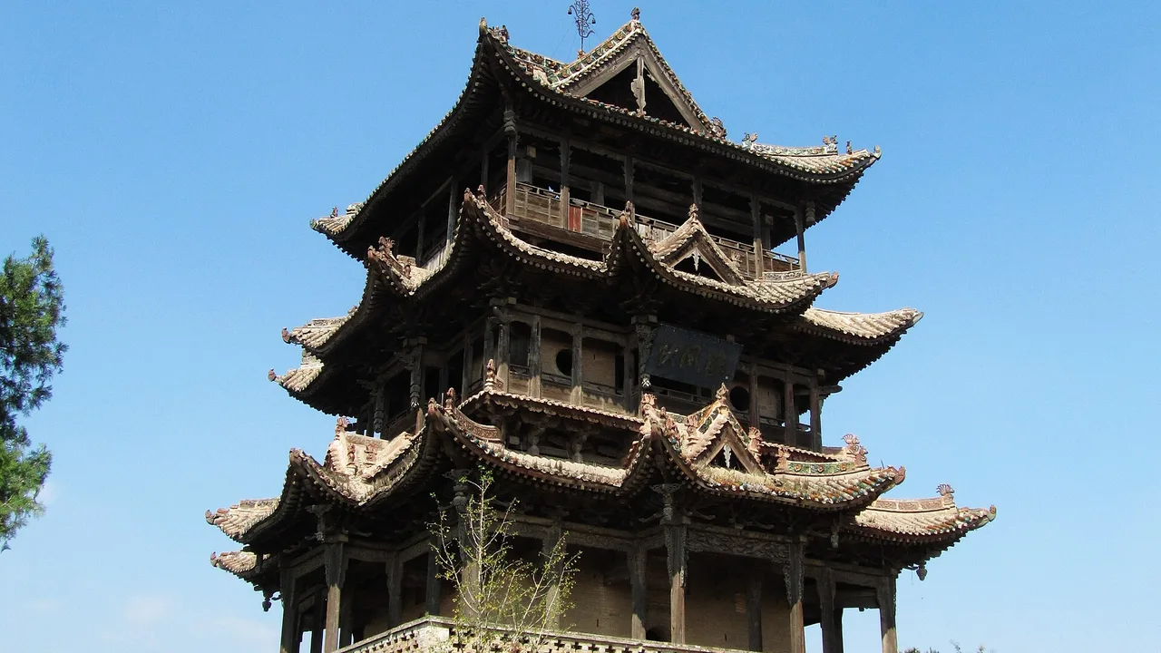 Qiufeng Pavilion at Wanrong's Houtu Temple, a tall cross-gabled tower on a high platform against a blue sky.