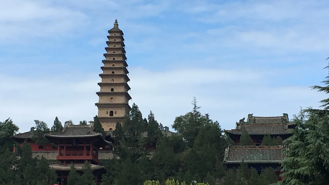 Yingying Pagoda rising above trees and halls at Pujiu Temple on its ridge near Puzhou, Yongji.